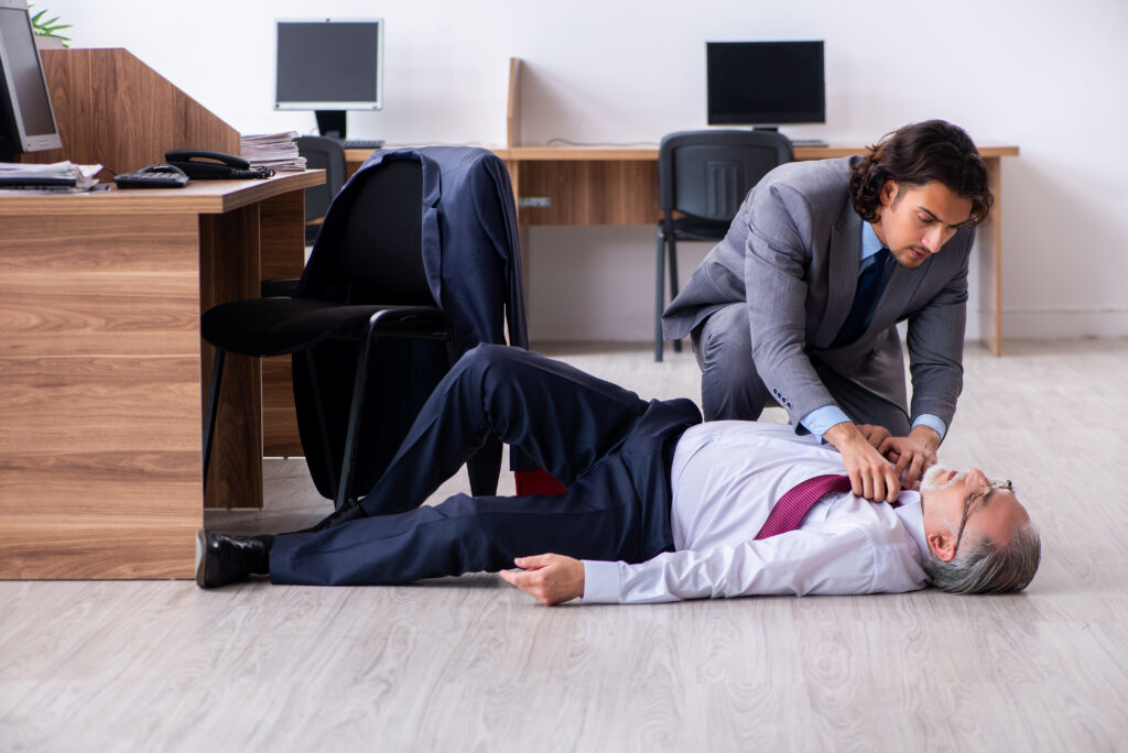 Ein Mann liegt bewusstlos auf dem Boden. Hierbei kann es sich auch um ein Arbeitsunfall im Homeoffice handeln.